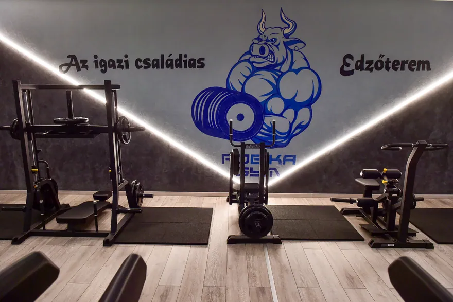 Edzőgépek a Robika Gym logós, családias edzőterem feliratú fala előtt