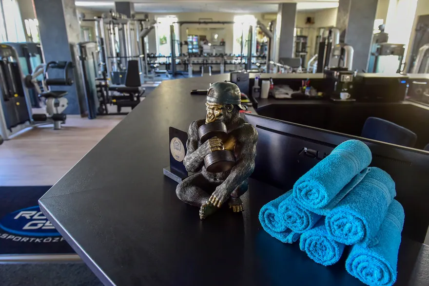 Kék törölközők és súlyzós figura a Robika Gym recepciós pultján